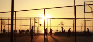 People playing basketball outside during a sunset
