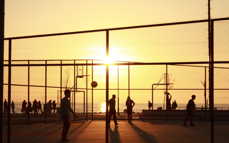 People playing basketball outside during a sunset